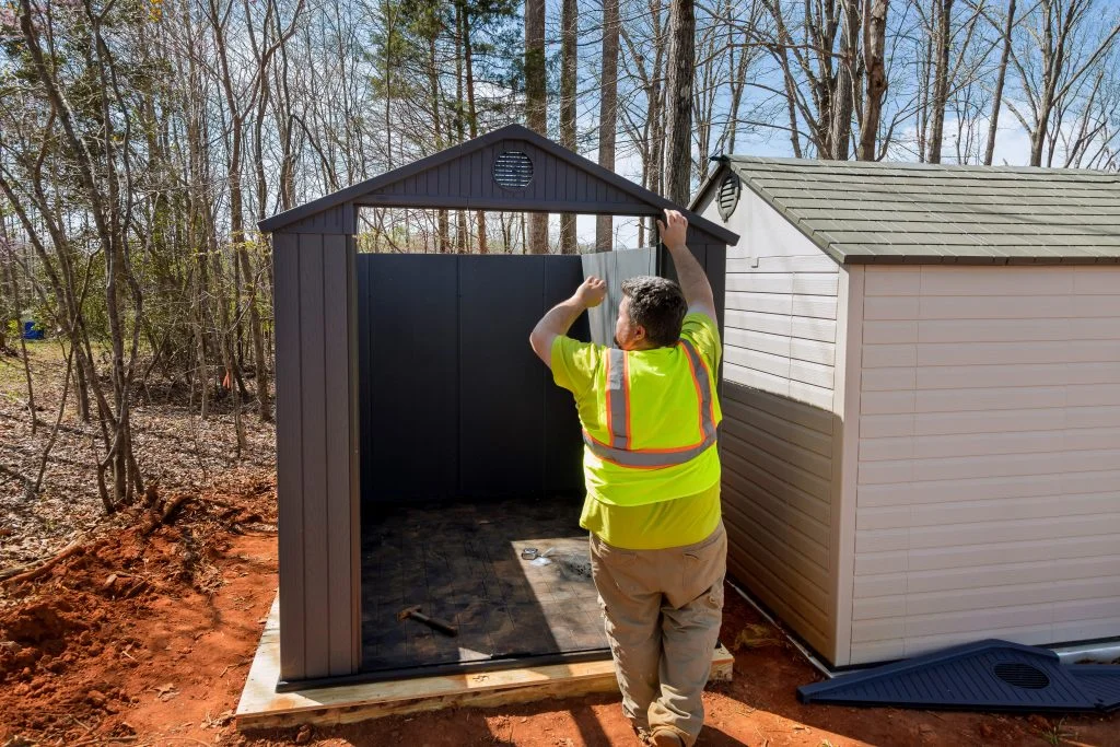 An individual assembles together plastic vinyl storage shed for his backyard